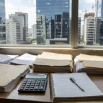 Mesa com pastas e calculadora em escritório imobiliário brasileiro para metas de vendas