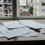 Documentos de contrato de intermediação imobiliária em mesa de escritório brasileiro